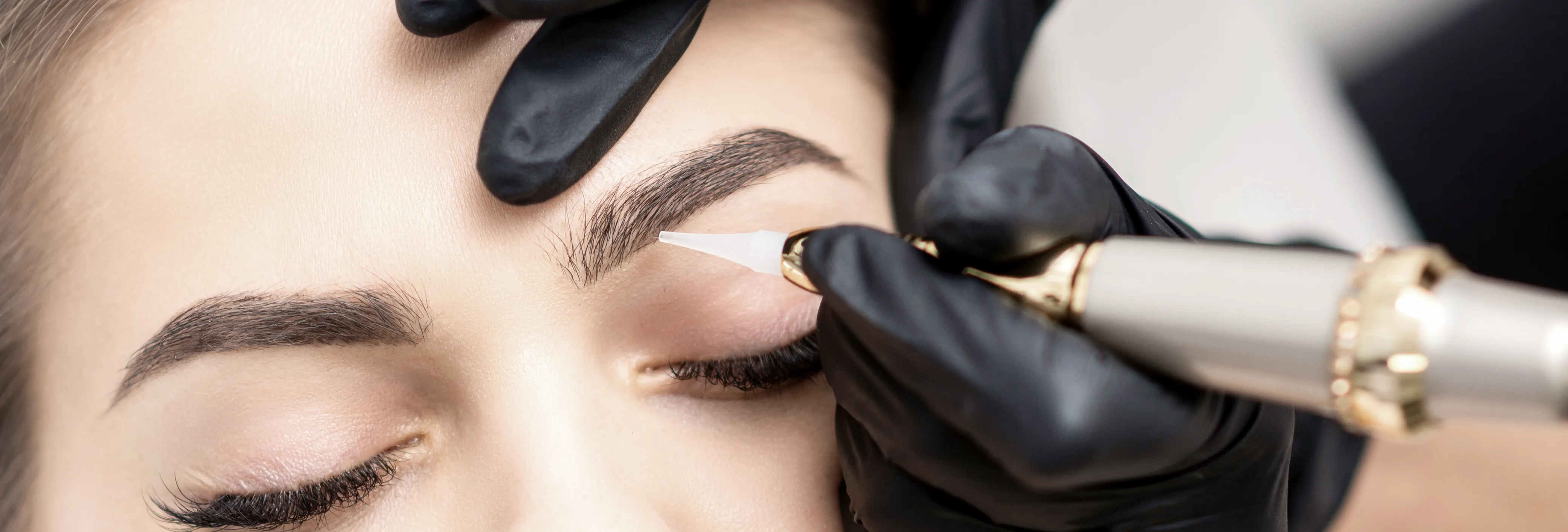 PMU machine drawing a hairstroke brow — procedure in studio